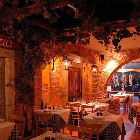 a restaurant with tables and chairs covered in checkered tablecloths is lit up at night