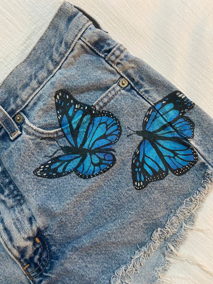 Short Pocket Painting, Jeans Painting Butterfly, Denim Short Painting Ideas, Fabric Painting Jeans, Fabric Paint Designs On Jeans, Denim Shorts Painting, Cute Fabric Painting, Painting Jean Shorts, Drawing On Shorts