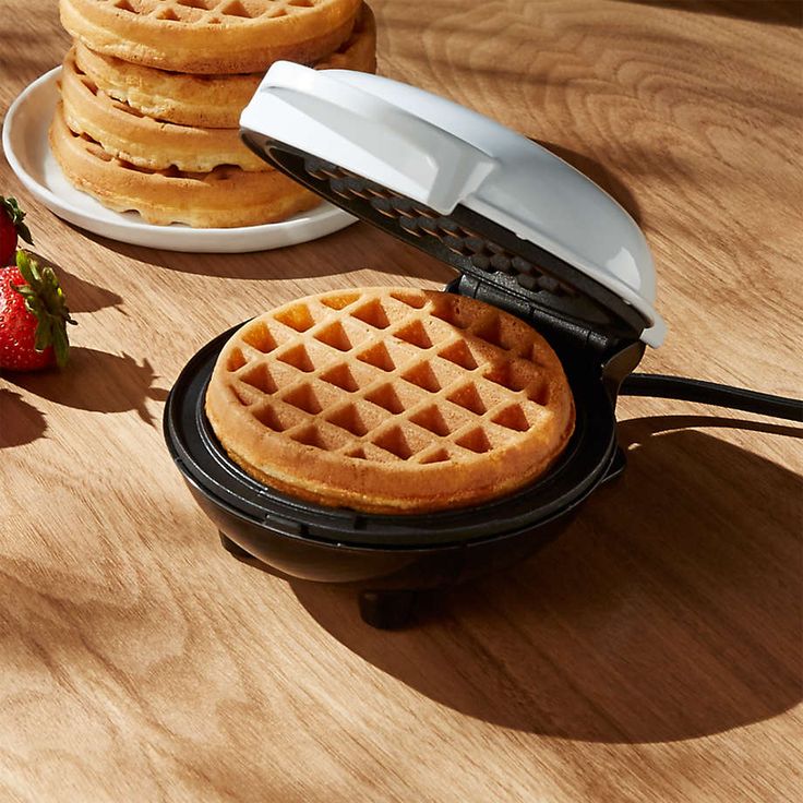 two waffles sitting on top of a wooden table next to a plate of strawberries