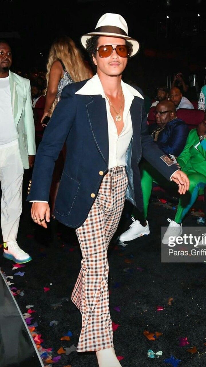 a man in plaid pants and a white hat walking through confetti covered ground