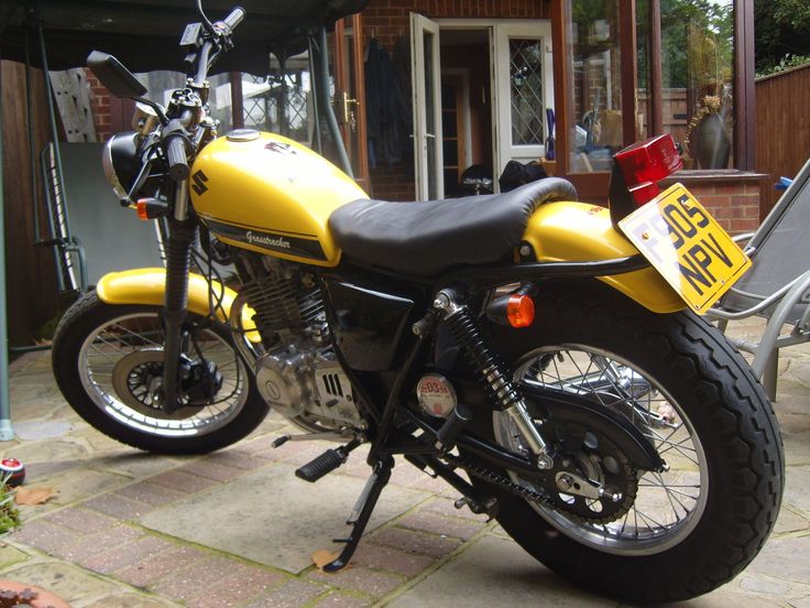 a yellow and black motorcycle parked in front of a house