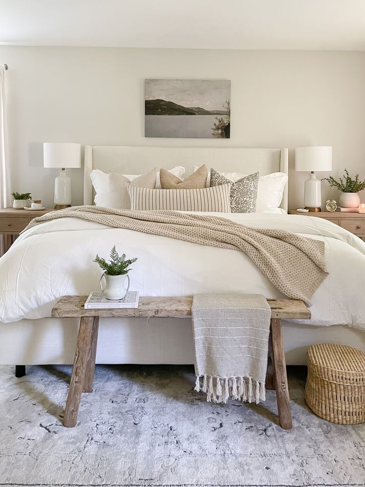 a bed with white linens, pillows and blankets on top of it in a bedroom