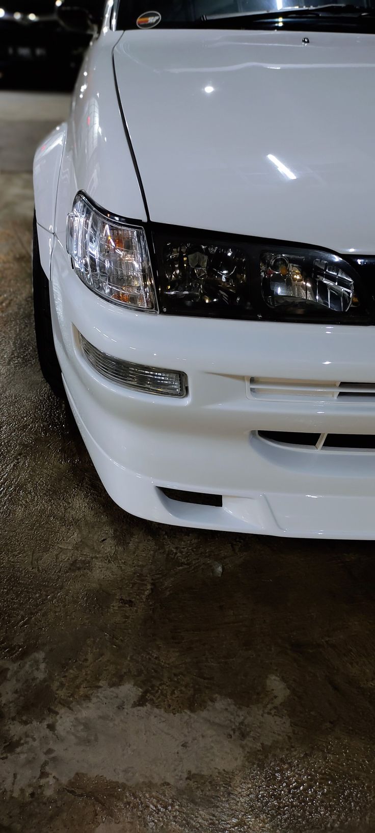 the front end of a white car parked in a garage