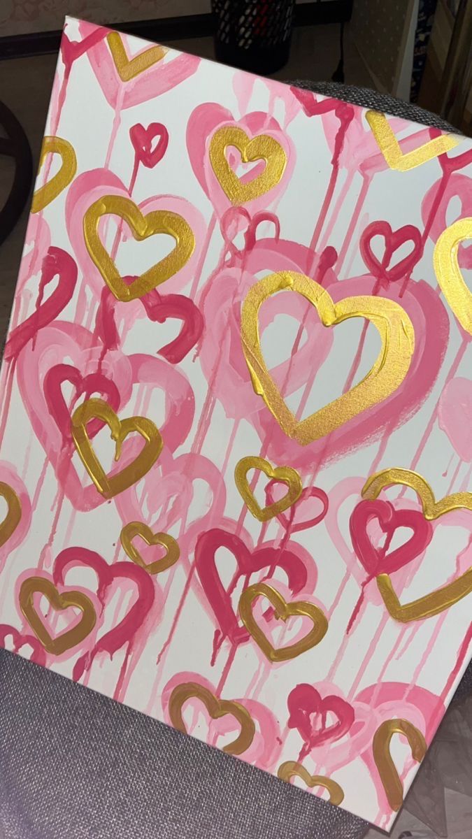 a painting with gold and pink hearts painted on it's side, sitting on a table