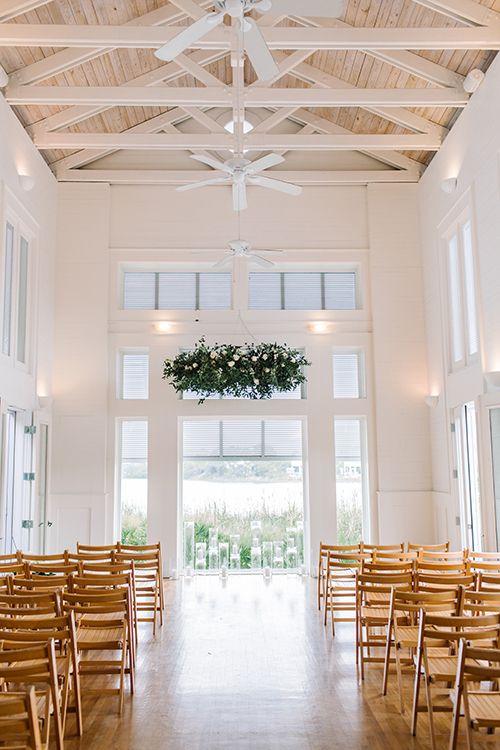 the inside of a church with wooden chairs and flowers hanging from the ceiling above them