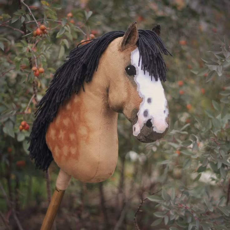 a brown and white horse with black mane standing in front of some bushes on a cloudy day