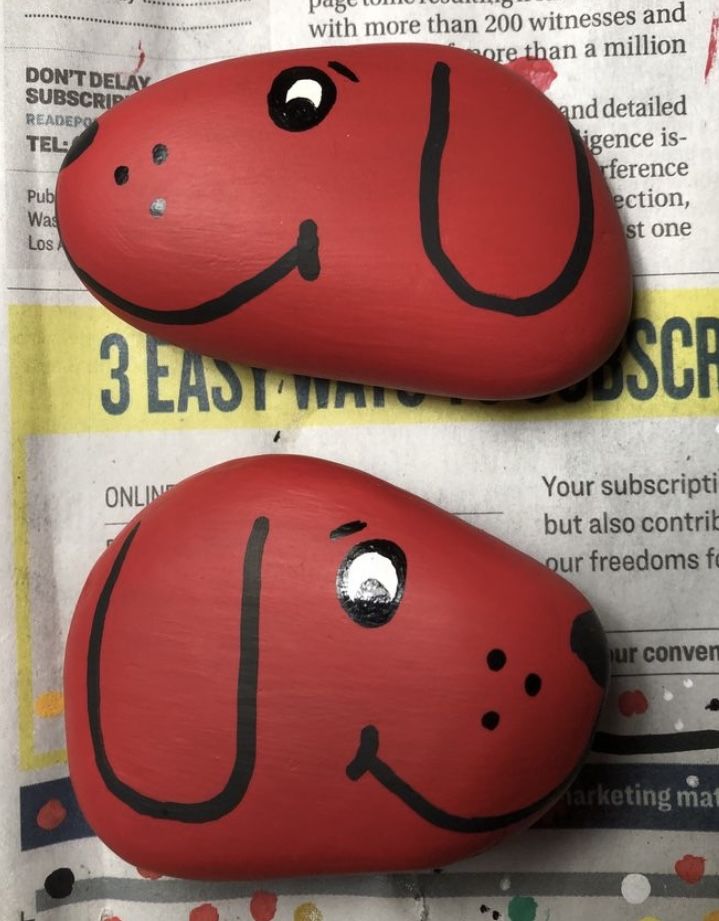 two red rocks with faces painted on them sitting next to each other in front of a newspaper