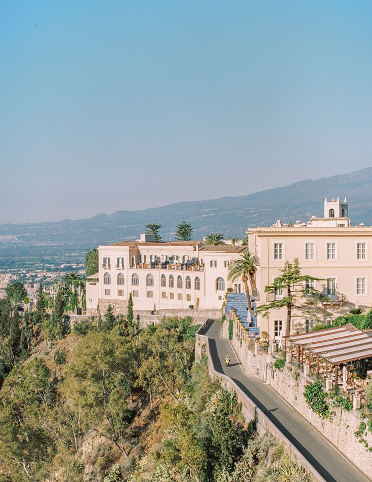 a large white building sitting on top of a lush green hillside