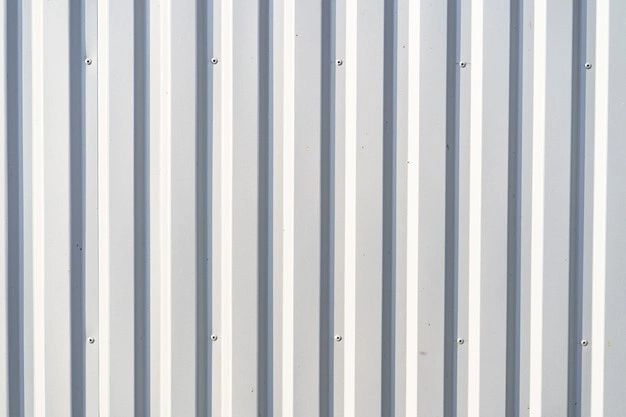 the side of a metal building with vertical lines painted on it's sides and an orange fire hydrant in front