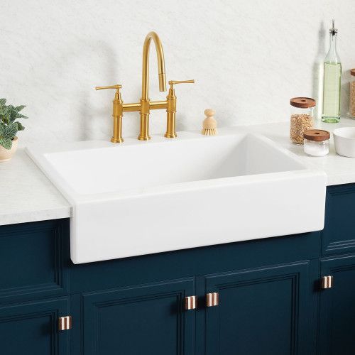 a white kitchen sink sitting under a faucet next to a counter top with soap dispensers