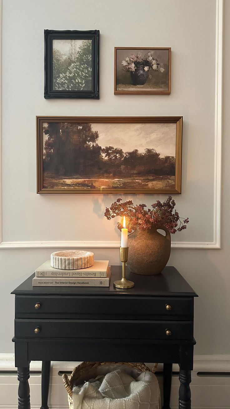 a black table with a candle and pictures on the wall above it in a living room