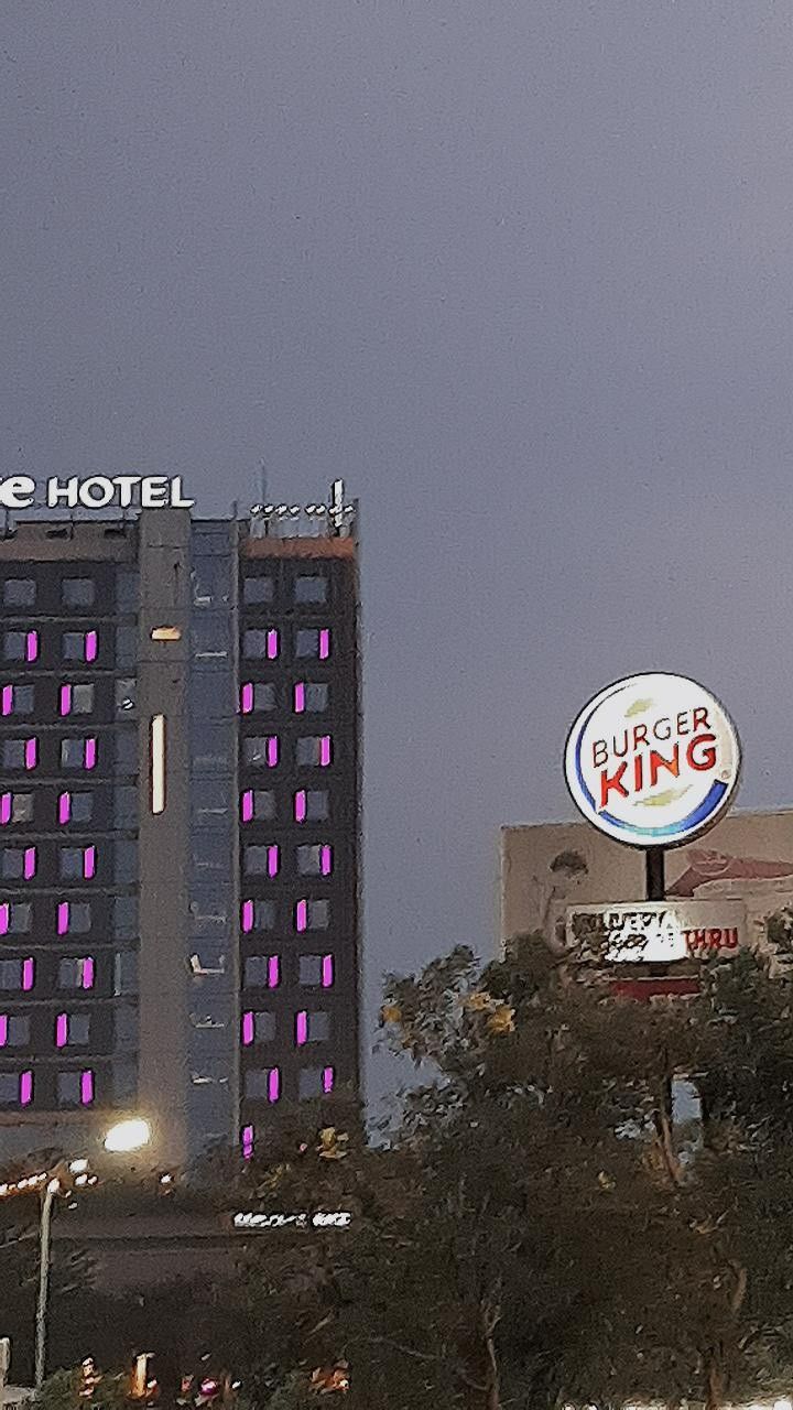 the hotel is lit up at night with purple lights on it's side and another building in the background