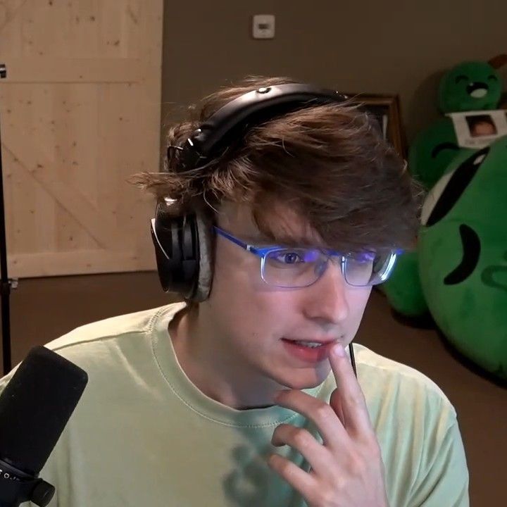 a young man wearing headphones while sitting in front of a green teddy bear and microphone