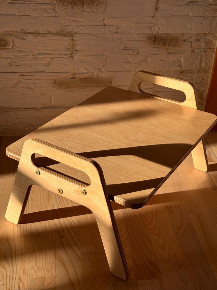 a wooden chair sitting on top of a hard wood floor next to a brick wall