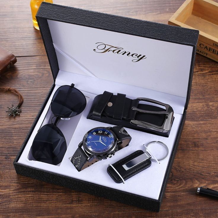 a watch, sunglasses and other items in a gift box on a table with a pen