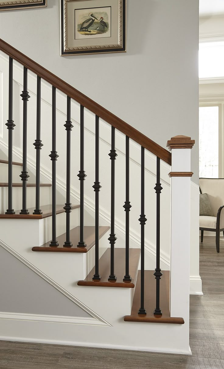 a staircase with wooden handrails and white painted walls in a home setting, along with framed pictures on the wall