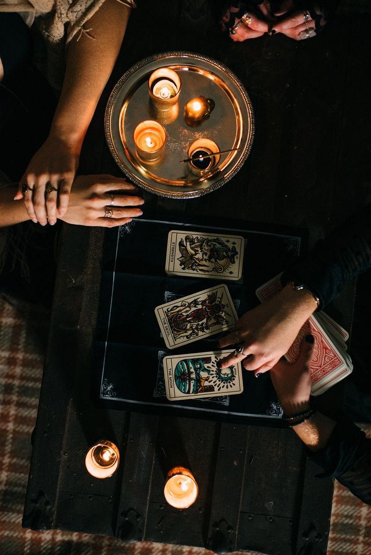 people sitting at a table with playing cards and candles