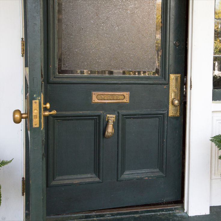 the front door is painted green and has gold trim on it's glass panels