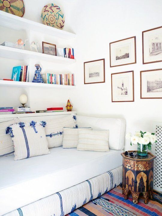 a living room with white couches and pictures on the wall above them, along with bookshelves