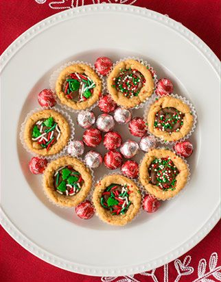 a white plate topped with mini christmas pies and candy on top of a red table cloth