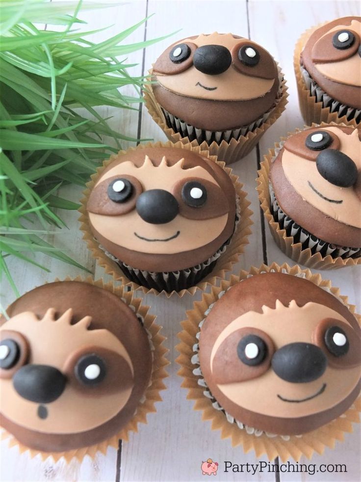 four cupcakes with chocolate frosting decorated to look like slotty faces and noses