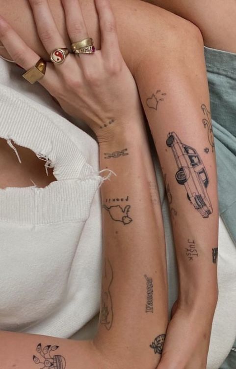 two women with tattoos on their arms sitting next to each other and one has her arm wrapped around the other