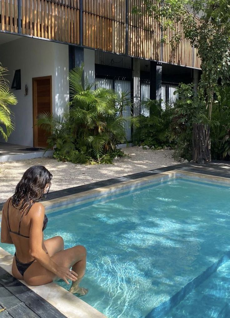 a woman sitting on the edge of a swimming pool