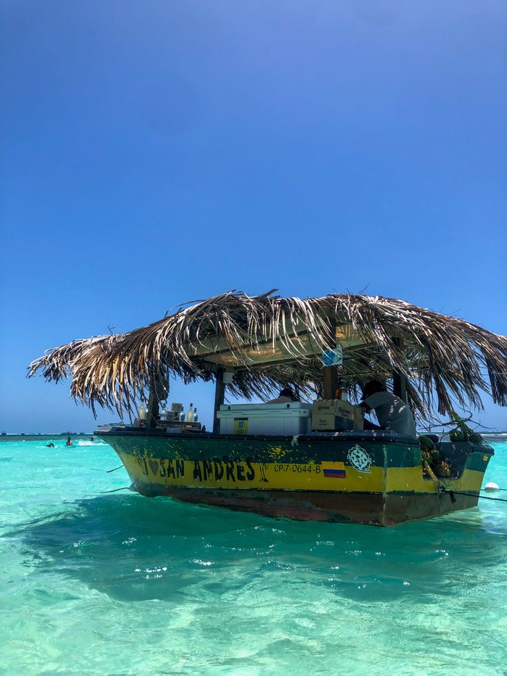 a yellow and black boat in the water with a thatch roof over it's head