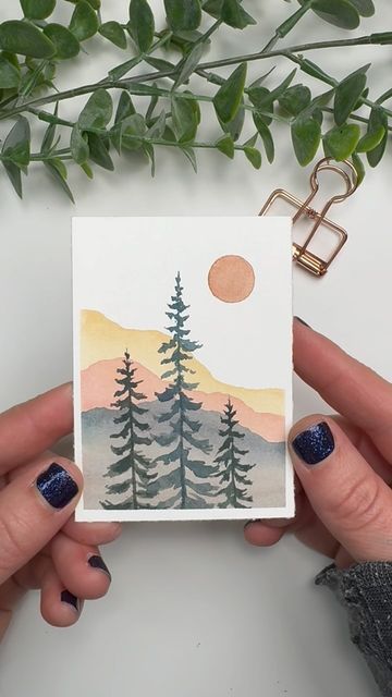 two hands holding up a card with trees on it