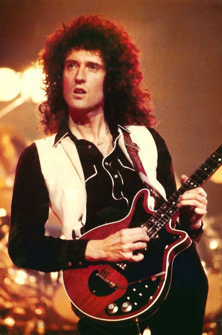 a man with long hair playing an electric guitar