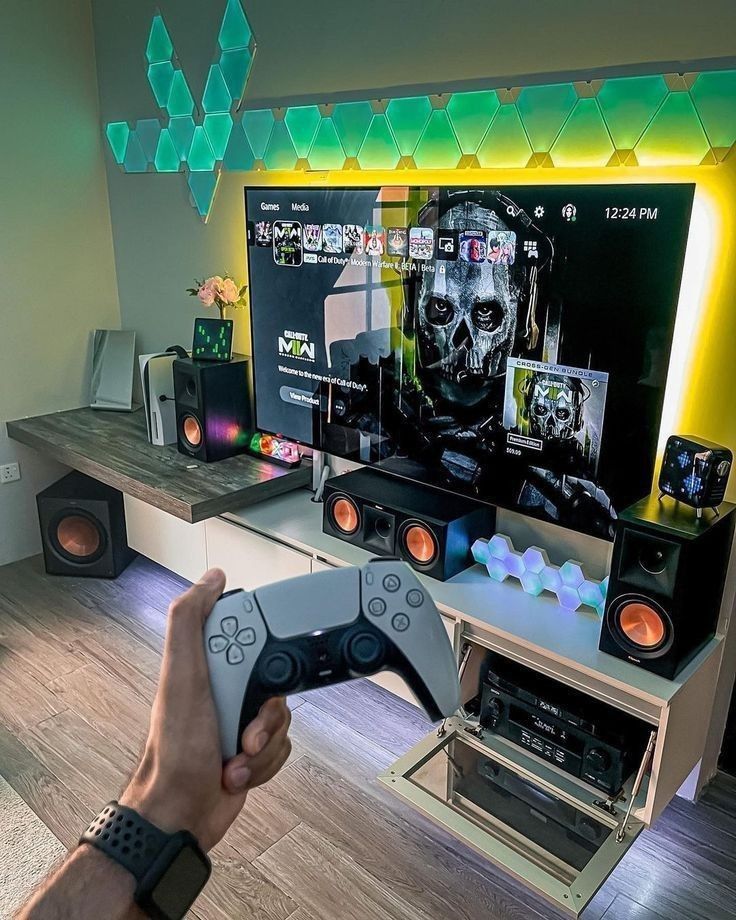 a person holding a video game controller in front of a flat screen tv with speakers