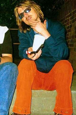 a man sitting on the ground with his hand over his mouth while holding a cell phone