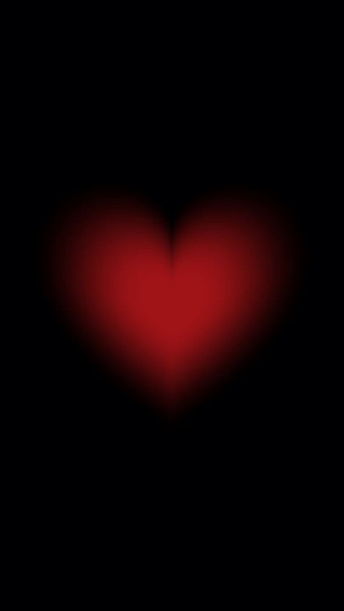 a red heart in the middle of a black background with only one light on it