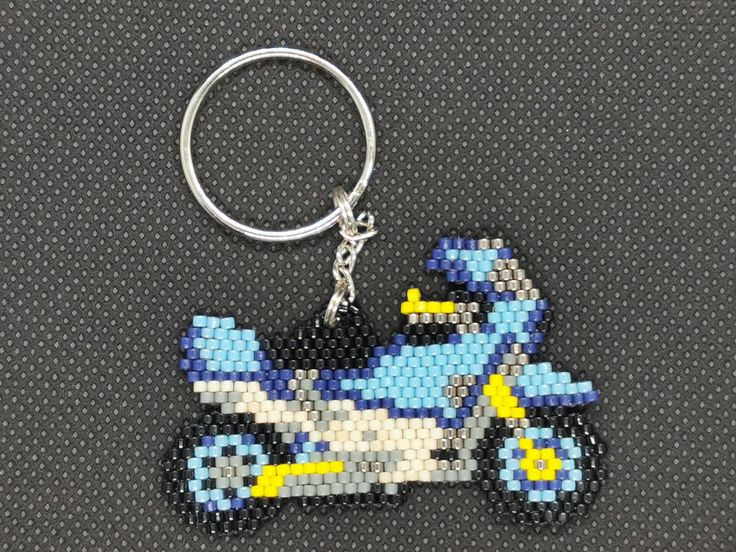 a key chain with a blue and white motorcycle on it's front end, sitting on top of a black surface