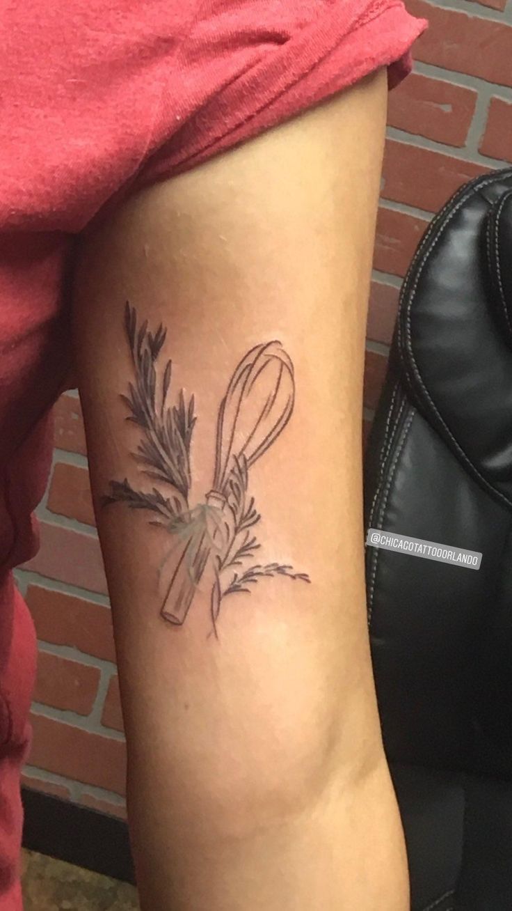 a woman's arm with a tattoo on it that has a knife and sprig