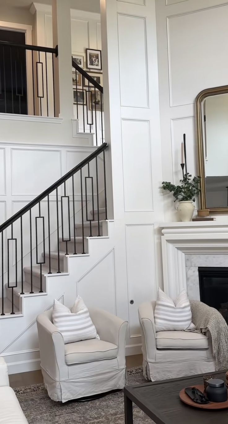 a living room filled with furniture and a fire place next to a stair case in front of a mirror