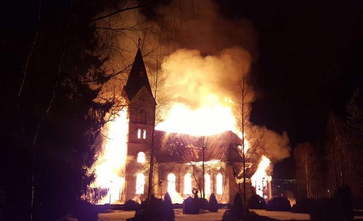 a church on fire at night with people around it