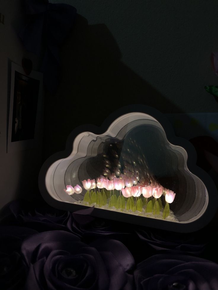 there is a cloud shaped mirror with toothbrushes in it and roses on the table