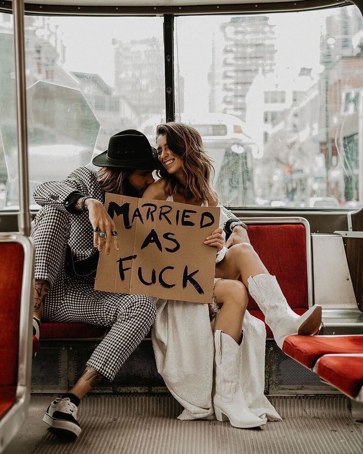 two women sitting on a bus holding a sign that says married as f ckk