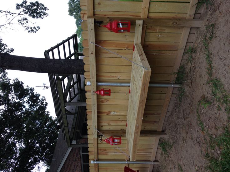 a wooden structure with red fire hydrants attached to it's sides next to a tree