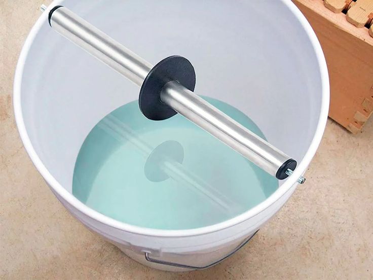 a white bucket filled with water next to a wooden pallet and some bricks on the ground