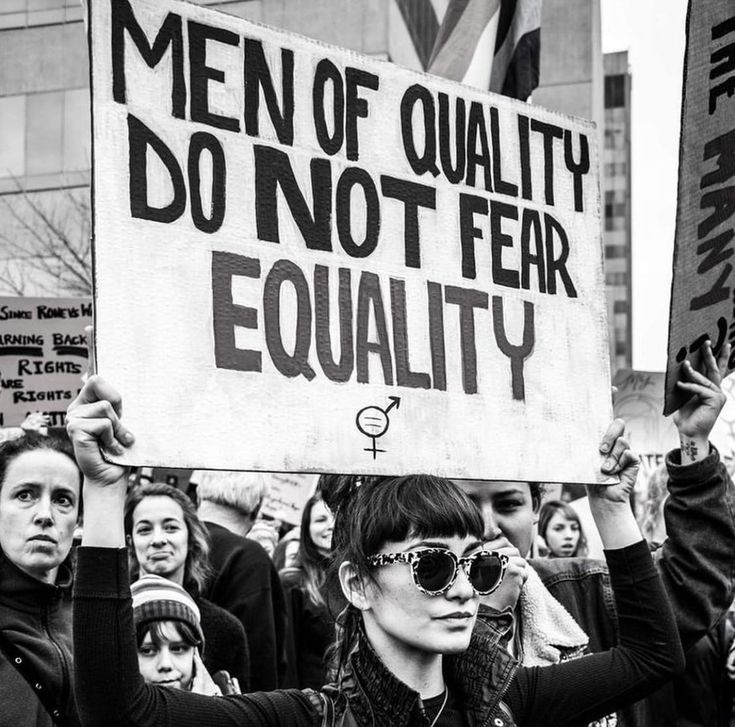 a group of people holding up signs in the middle of a street with men of quality do not fear equality