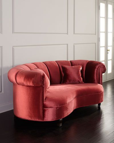 a red couch sitting on top of a hard wood floor next to a white wall