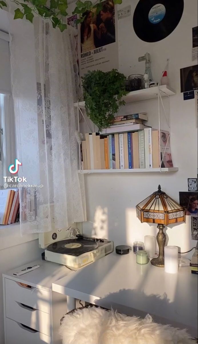 a white desk with a record player, lamp and books on the shelf next to it