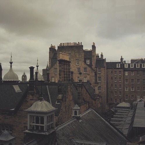 an aerial view of some buildings in the distance with dark clouds overhead and rain falling on them