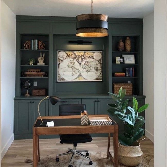 a home office with built in bookcases and a large potted plant on the desk