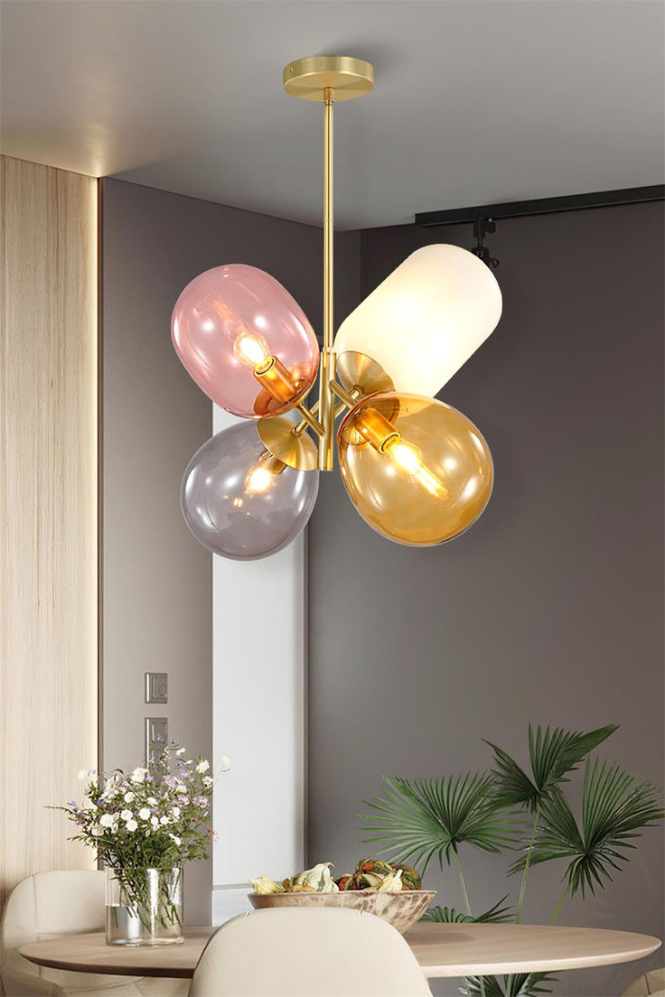 a modern chandelier hanging from the ceiling in a dining room with round table and white chairs