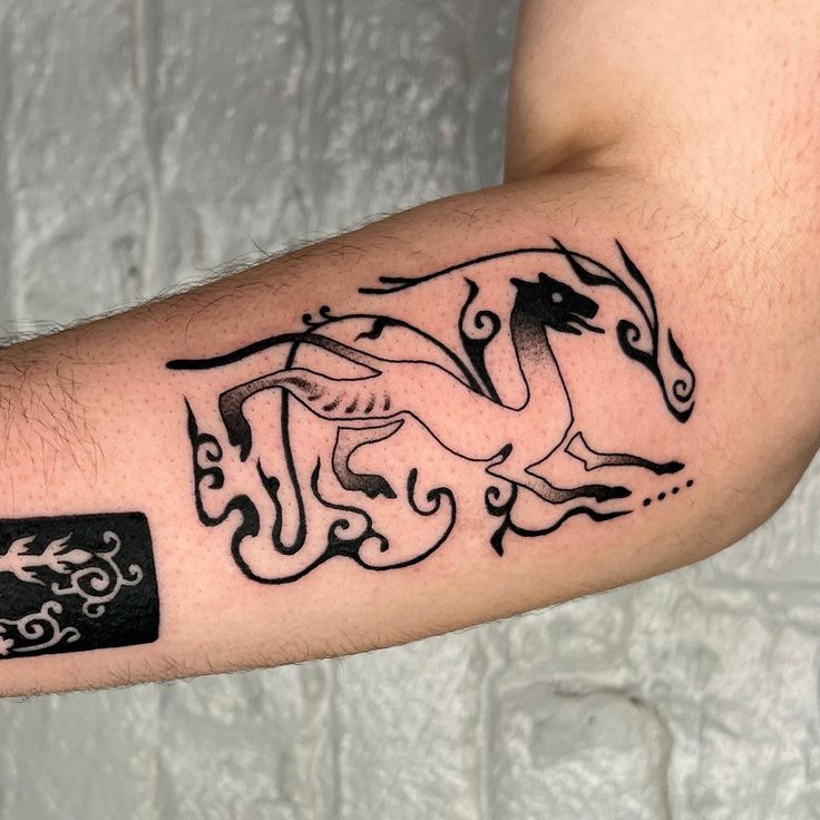 a man's arm with a horse tattoo design on the left side of his arm