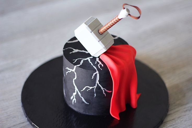 a black and white hat with a hammer sticking out of it's top on a wooden table