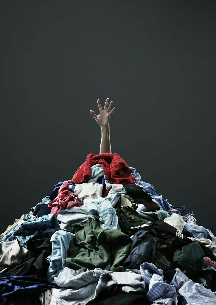 a pile of clothes with one hand up above the top